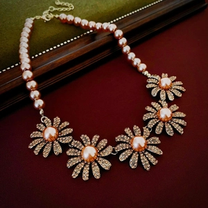 Detailed macro view of daisy flower charms with sparkling crystals and pink pearls on a gold necklace