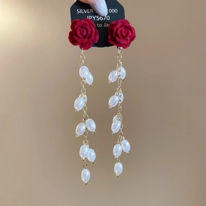 Detail of red flocked rose earrings with white pearl tassels and silver needle posts