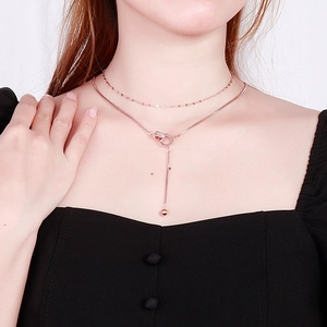 Double-layered rose gold necklace featuring interlocking circles and tassel pendant