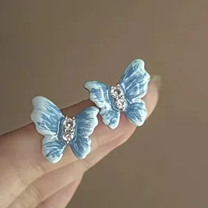 Vue détaillée des boucles d'oreilles papillon en émail bleu ornées de strass brillants