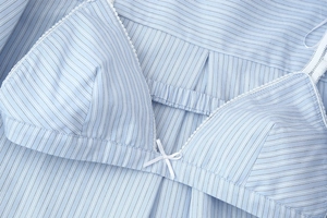 Detailed close-up of light blue striped top featuring white lace trim and a small bow