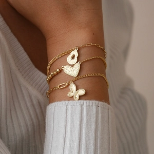 Close-up of three gold bracelets with heart, butterfly and gourd hammered metal charms