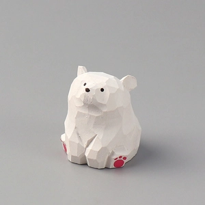 Macro shot of hand-carved white wooden polar bear with minimalist facets and pink paw prints