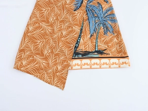 Detail of tropical coconut tree print on asymmetrical dress hem with white leaf motifs