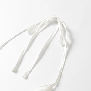 Détail macro du ruban en satin blanc lisse sur un ensemble élégant de trois pièces
