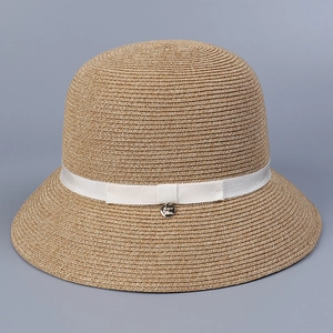 Detailed close-up of straw sun hat texture with white ribbon bow and metal logo tag