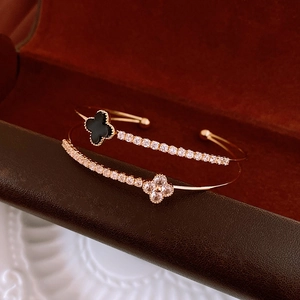 Detail of double-layered gold bangle with black clover and pavé zircon stones in a red box