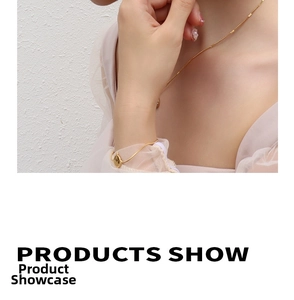 Detailed close-up of a minimalist gold necklace and bracelet set on a textured white background