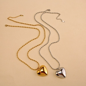 Close-up of gold and silver heart pendants on bead chains with lobster clasps