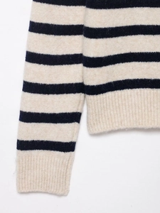 Detailed close-up of navy and cream striped knit sweater showing ribbed cuffs and texture