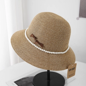 Detail showing UV CUT tag and elegant pearl chain decoration on woven sun hat