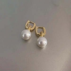 Détail de boucles d'oreilles pendantes dorées ornées de perles blanches rondes