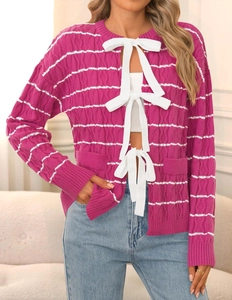 Detail of fuchsia knit cardigan with white horizontal stripes and three large bow ties