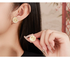 Macro shot of gold lotus leaf earrings with brushed metal texture and sparkling zircon edges