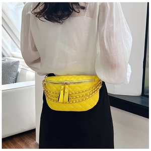 Detail of yellow quilted waist bag with gold chain accents and dual zippers on a model