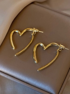 Macro detail of minimalist gold heart earrings showing hollow lines and polished finish
