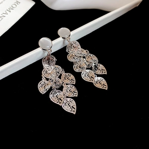 Detailed shot of silver leaf drop earrings with white cat-eye stones and cut-out design