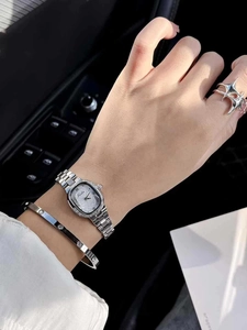 Close-up of a silver watch with rhinestone bezel paired with a screw-detail bangle and ring