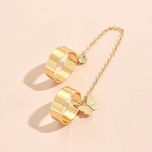 Detailed close-up of golden dual rings connected by chain with butterfly and gem charms