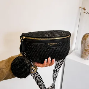 Detail of black woven crossbody bag with golden zipper and geometric wide shoulder strap
