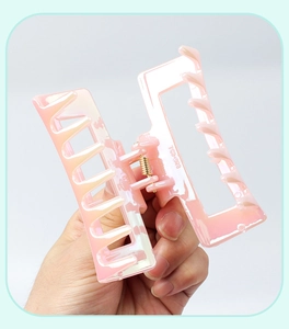 Handheld view showing dimensions of a hollow rectangular jelly pink hair claw clip