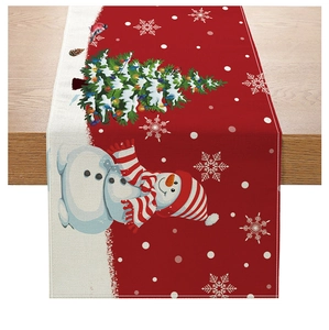Detail of Christmas table runner with snowman and tree print on linen texture fabric