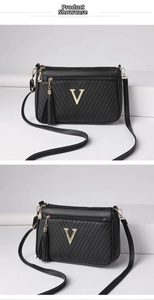 Detailed view of women black leather shoulder bag with metal V logo and chic tassel pendant.