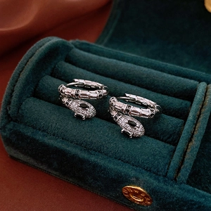 Detail of luxury zircon snake earrings set in a dark green velvet jewelry box