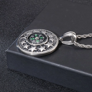 Macro shot of a silver stainless steel compass pendant with star on a black textured box