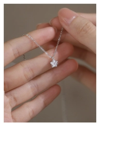 Close-up of star-shaped zircon pendant with polished silver chain on fingers