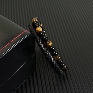 Detail shot of men's hand-woven black leather bracelet with red tiger eye and onyx beads