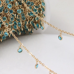 Macro detail of gold plated jewelry chain with round sky blue gemstone charms