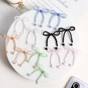Detail of handcrafted beaded bow earrings in multiple colors on a white plate