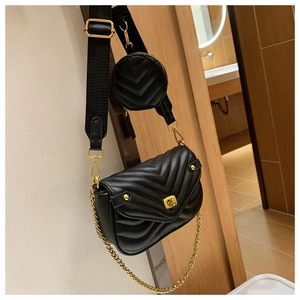 Detail of black quilted crossbody bag with gold chain and round coin purse attachment