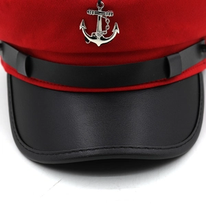 Detail of red captain hat with black leather brim and silver anchor metal pendant