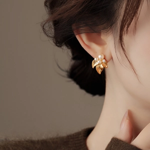 Detail of vintage leaf pearl earrings featuring gold leaf design on a model's ear