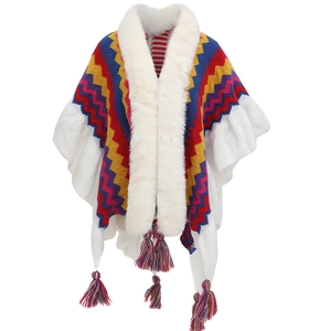 Detail of colorful wave pattern knit poncho with white faux fur collar and tassels