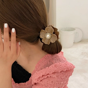 Detailed view of a brown resin flower hair claw clip with a faux pearl center on hair
