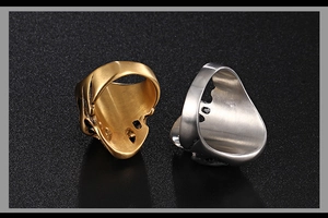 Detailed view of punk style skull rings in gold and silver finish on matte background