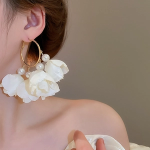 Detail of floral tassel earrings with white pearls and gold hoops on model