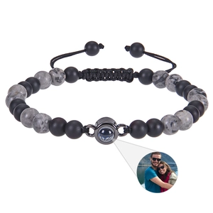 Detail of custom photo projection bead on matte black and marble stone braided bracelet