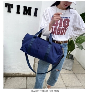 Detail of dark blue nylon travel bag with pleated design and adjustable shoulder strap