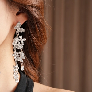 Macro detail of silver butterfly earrings with sparkling crystals and tassel drop on model
