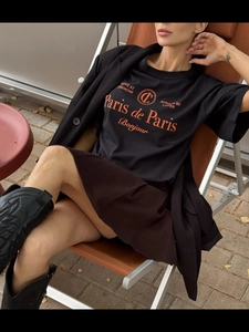 Λεπτομέρεια μαύρου βαμβακερού t-shirt με πορτοκαλί γράμματα Paris de Paris τυπωμένα