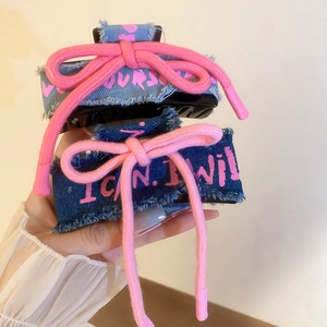 Close-up of denim hair claw clips with pink cotton bow knots and text embroidery