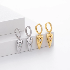 Detail of gold and silver hoop earrings featuring evil eye heart charms and opal stones