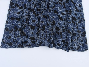 Détail d'une robe noire élégante avec broderie florale bleue et texture de dentelle