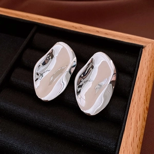 Close-up of irregular oval liquid metal earrings on black velvet in a jewelry box