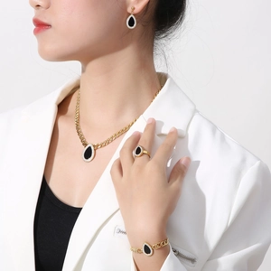 Close-up of gold stainless steel jewelry set with black teardrop pendants and crystals