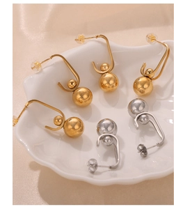 Detailed shot of gold and silver U-shaped earrings with dual beads on silk fabric